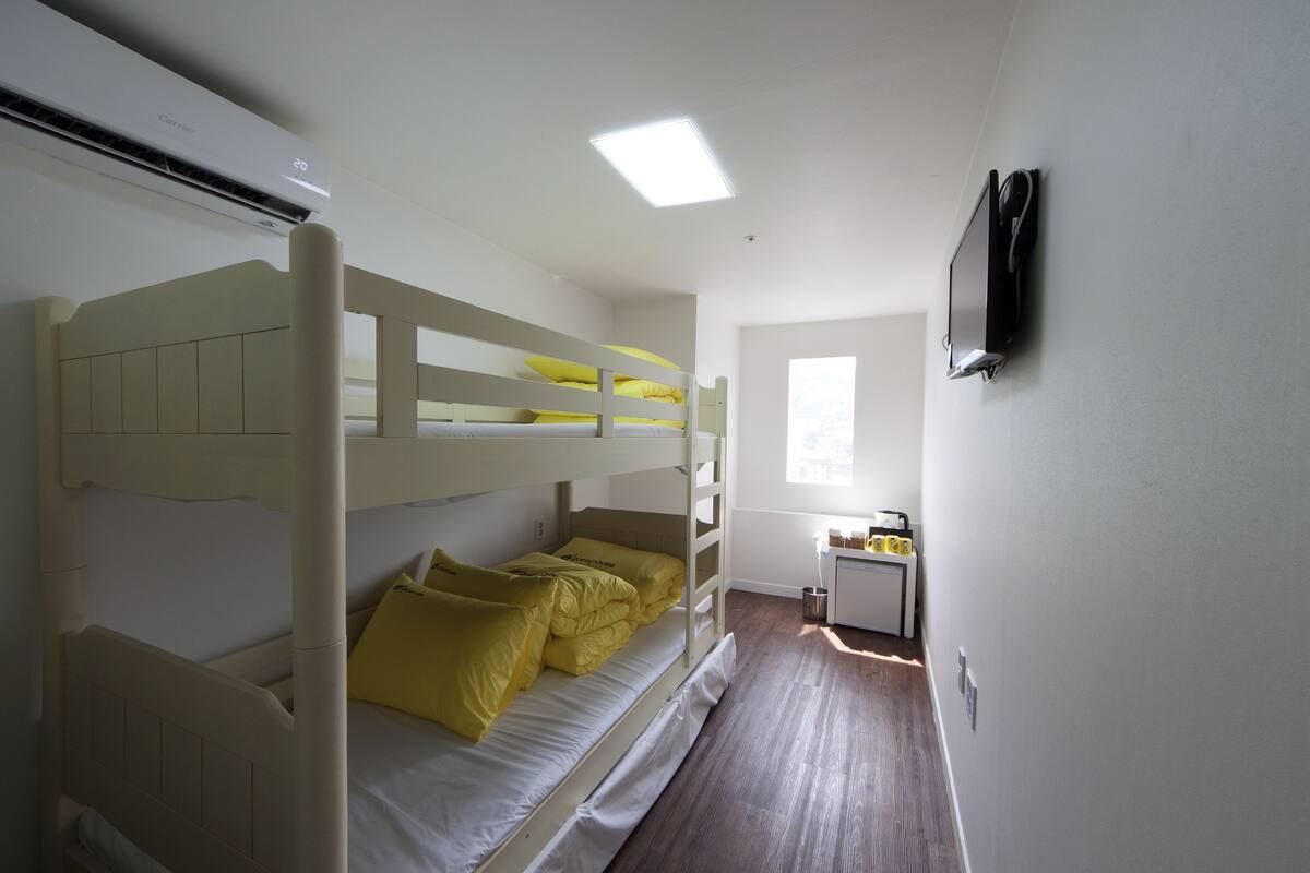 A bunk bed room with a desk and a window.