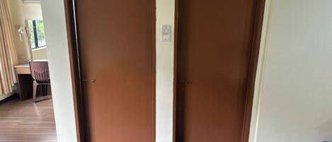 Entrada de hotel con dos puertas marrones, un felpudo y una cesta de plástico en el suelo.