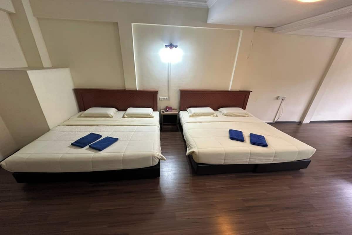Une chambre avec deux lits, chacun doté d’une tête de lit et d’une table de chevet.