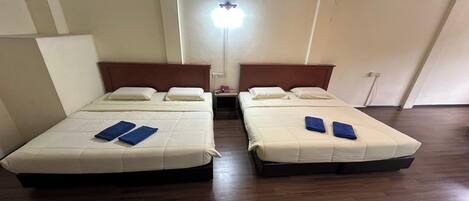 Una habitación con dos camas, cada una con cabecera y mesita de noche.