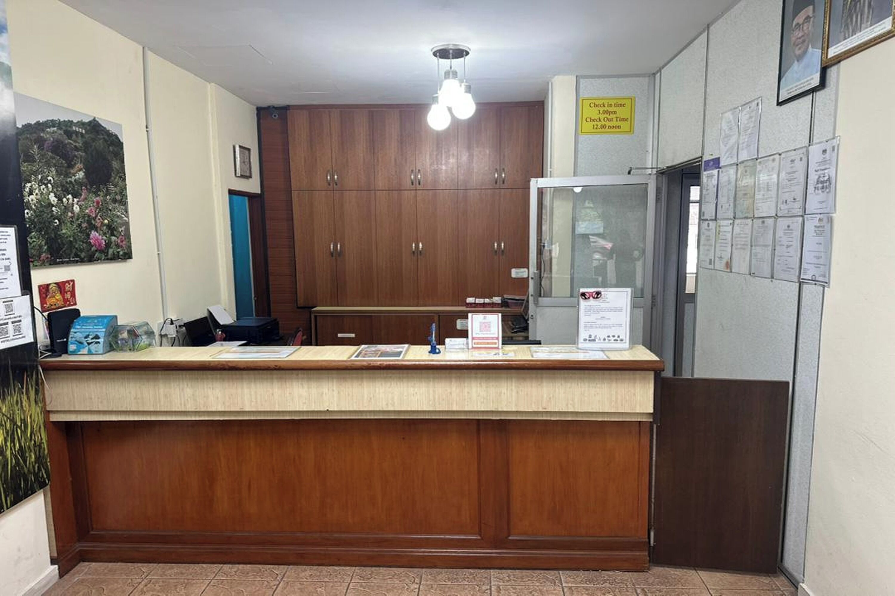 A reception desk with a wooden counter, a glass display case, and a wall with various notices and papers.