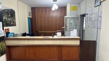 A reception desk with a wooden counter, a glass display case, and a wall with various notices and papers.