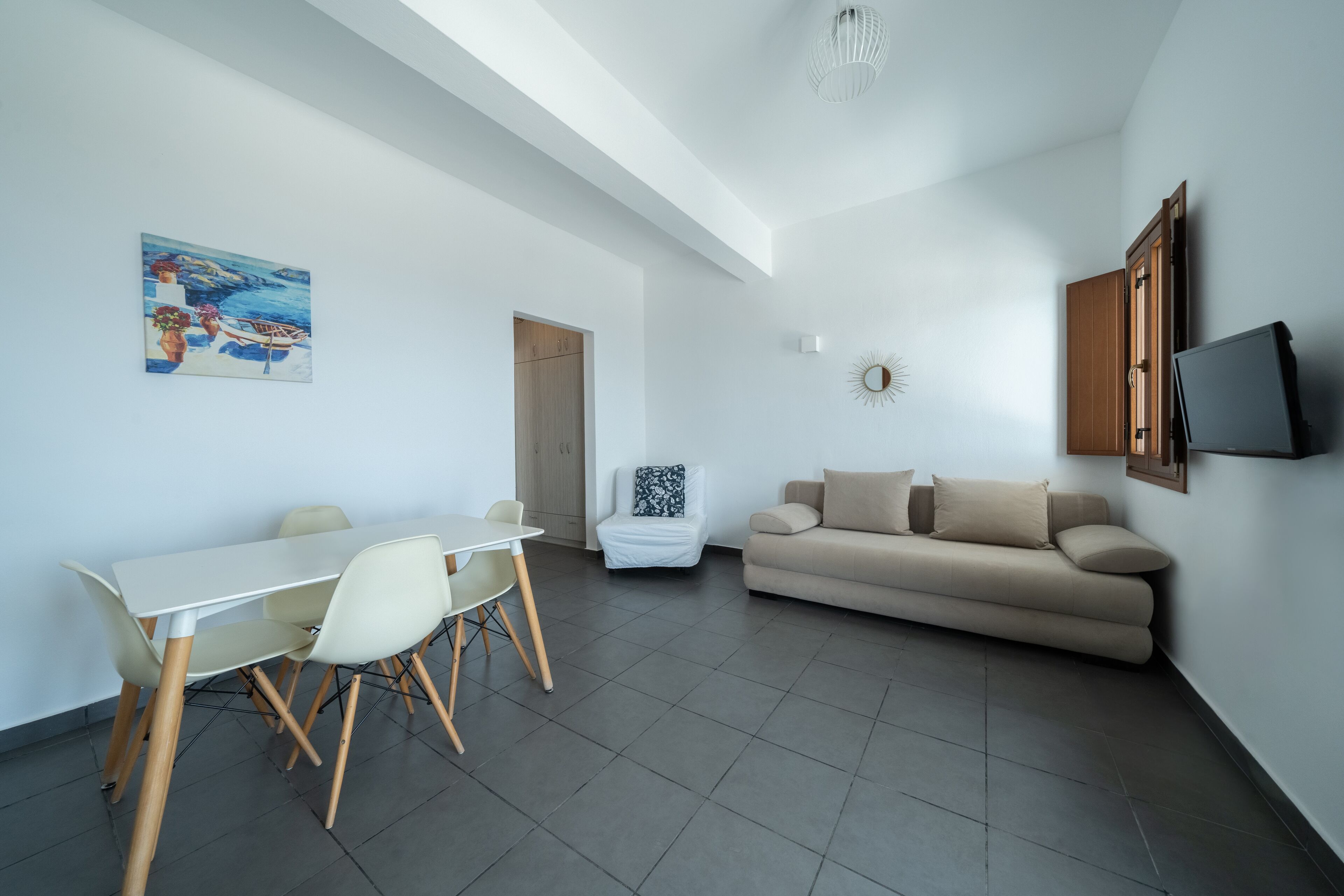 Ein modernes Wohnzimmer mit Essbereich, einer Couch, einem an der Wand montierten Fernseher und einem Gemälde.