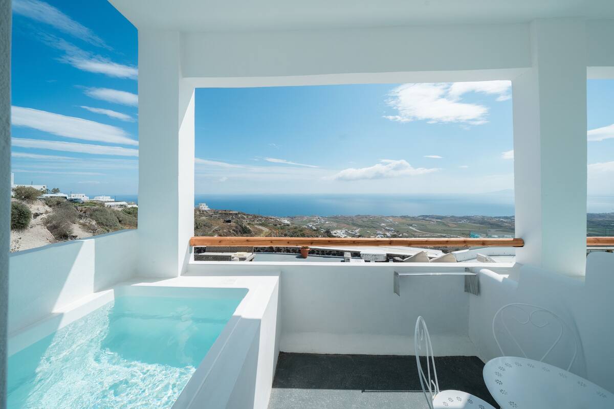 Un balcon avec vue sur la mer, une baignoire, ainsi qu’une petite table et une chaise.
