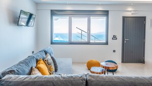 Een moderne woonkamer met een groot raam, een grijze bank en een klein houten tafeltje.