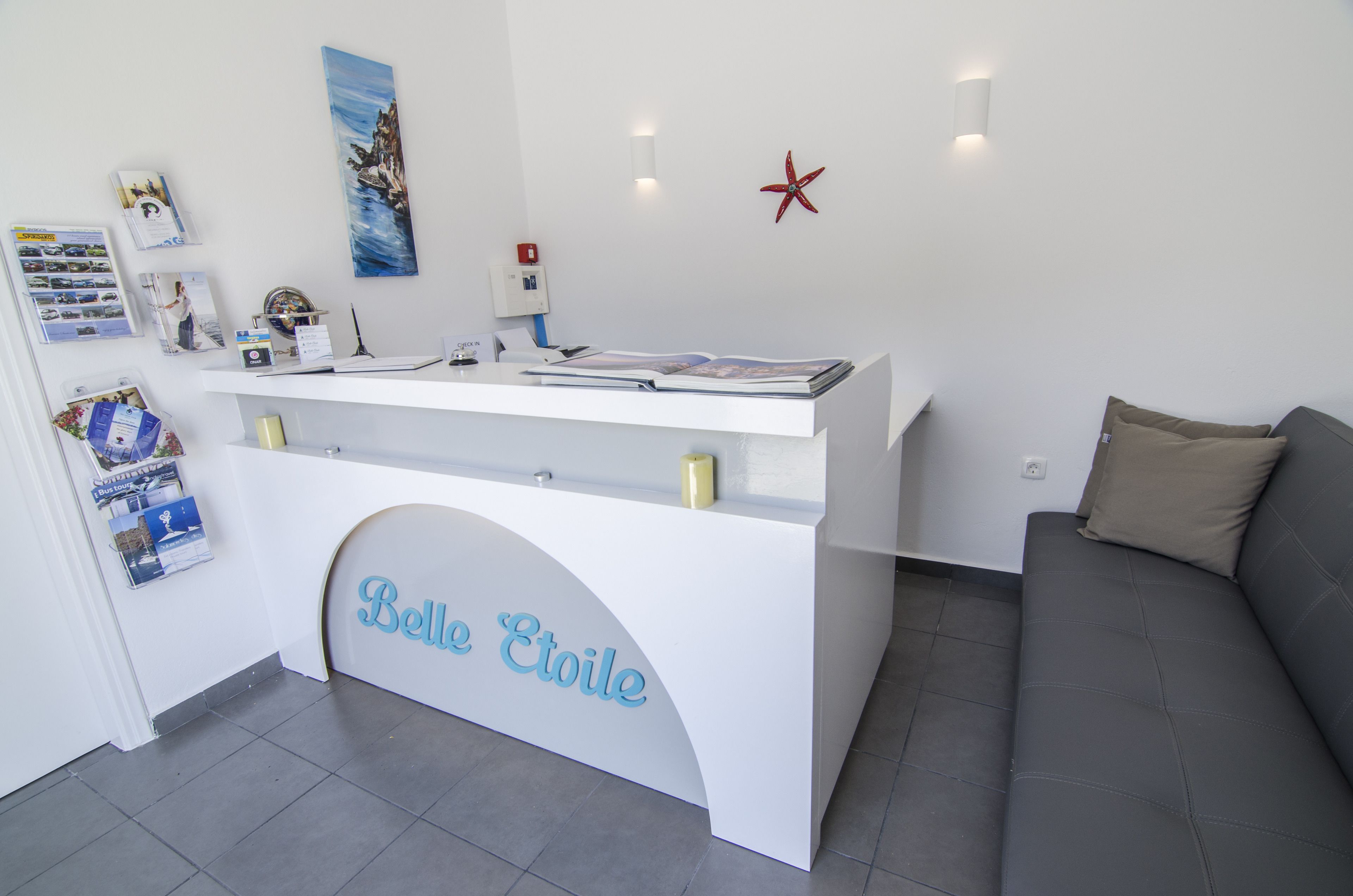 Una mesa de recepción con un letrero que dice "Belle Etoile", un sofá gris y una pared decorada con una estrella de mar.