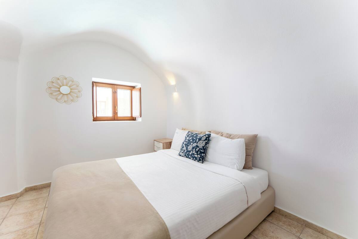 Une chambre à coucher avec un lit, une table de chevet, une fenêtre et un élément décoratif mural.