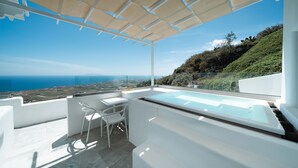 Een modern terras buiten met een jacuzzi, witte meubels en een schilderachtig uitzicht op de oceaan.