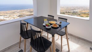 Een eetgedeelte met een tafel en stoelen, uitzicht op zee en een betegelde vloer.