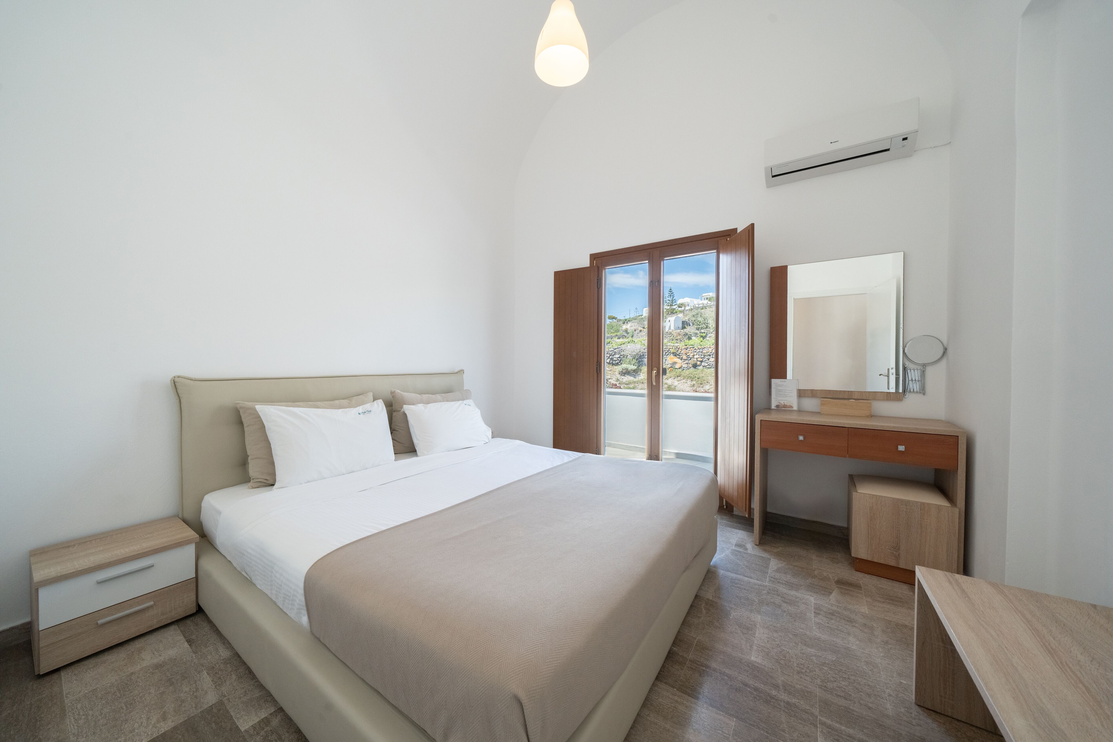 Une chambre à coucher comprenant un lit, une table de chevet, une commode et une grande fenêtre donnant sur un beau paysage.