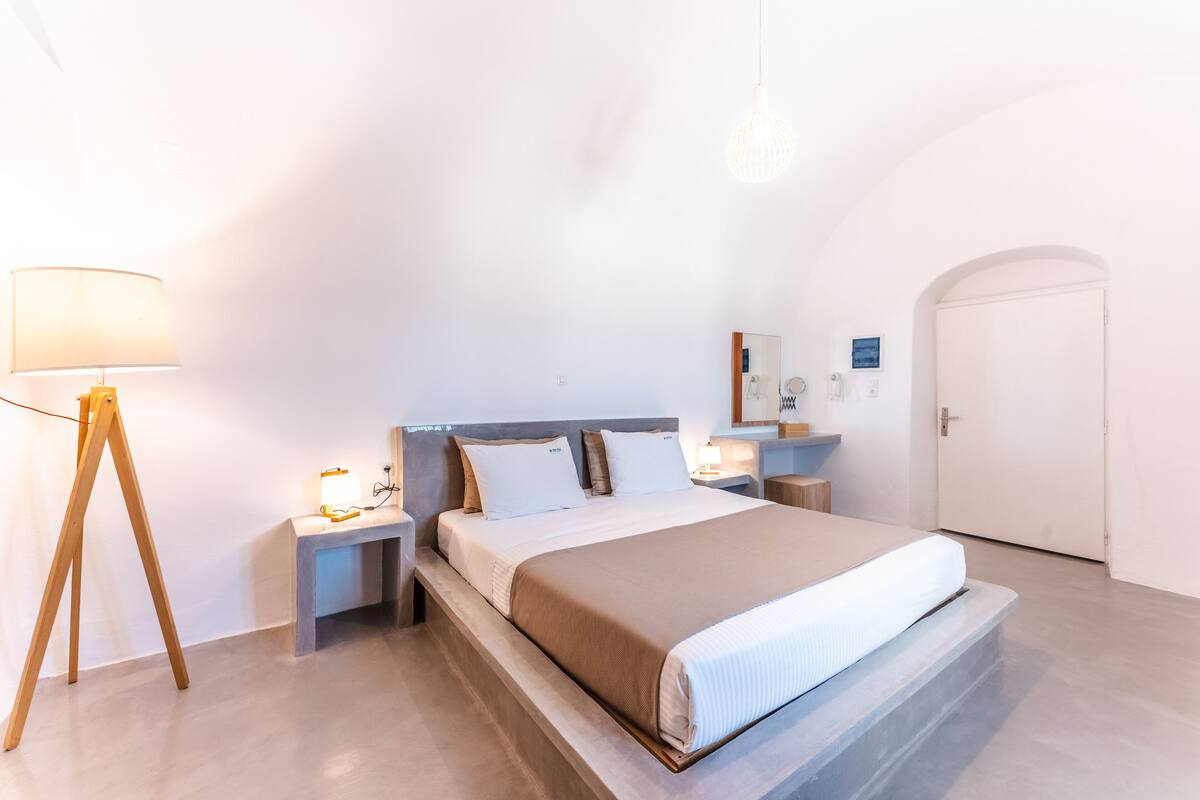Une chambre à coucher moderne avec un lit, des tables de chevet, une lampe et une porte.