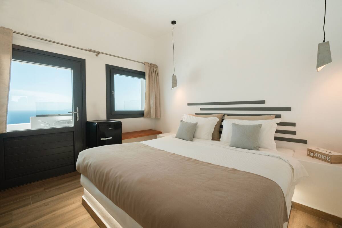 Une chambre à coucher moderne avec un grand lit, une table de chevet, une commode et une fenêtre donnant sur un beau paysage.