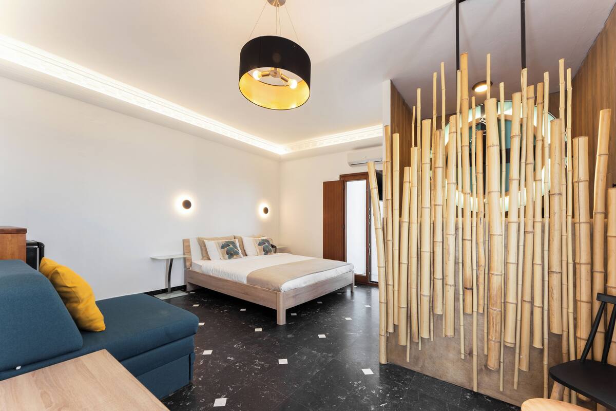 Une chambre d’hôtel moderne équipée d’un lit, d’un canapé, d’une table et d’un mur décoratif en bambou.