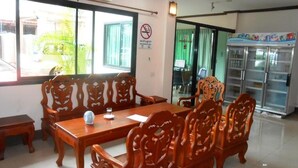 Un salón de conferencias con una mesa y sillas de madera, un refrigerador y una ventana con vista a follaje.