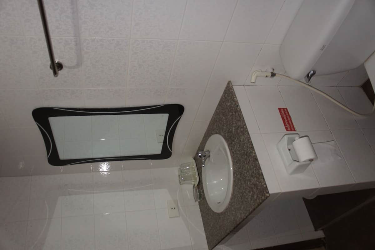 A bathroom with a rectangular mirror, a sink, and a toilet.
