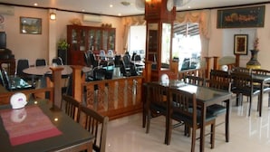 Un restaurante con varias mesas y sillas, un pilar decorativo de madera y ventiladores de techo.