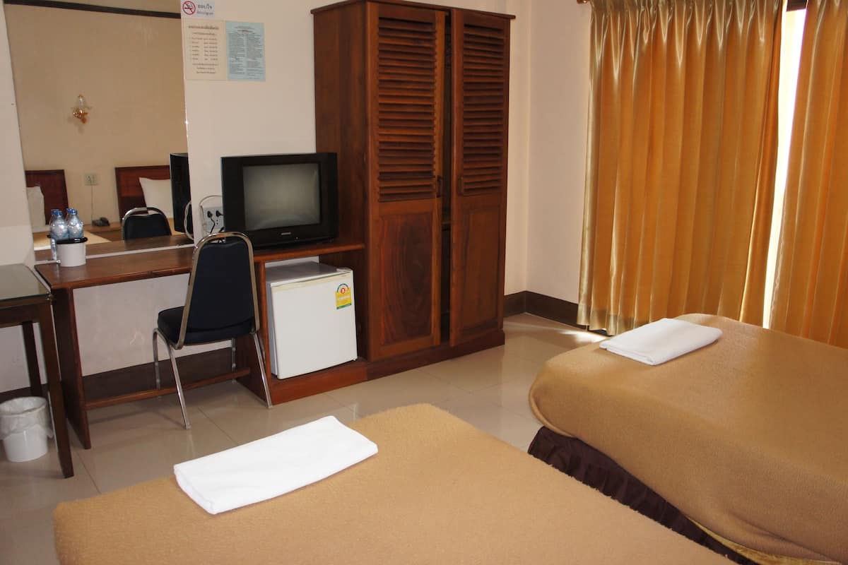 A hotel room with a bed, a desk with a television, a small refrigerator, and a wardrobe.