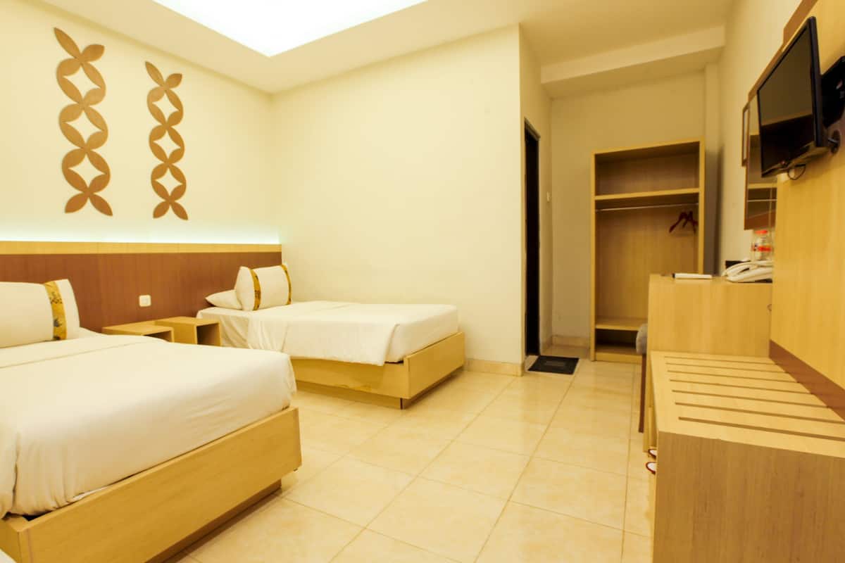 Een hotelkamer met twee bedden, een televisie en een kledingkast.