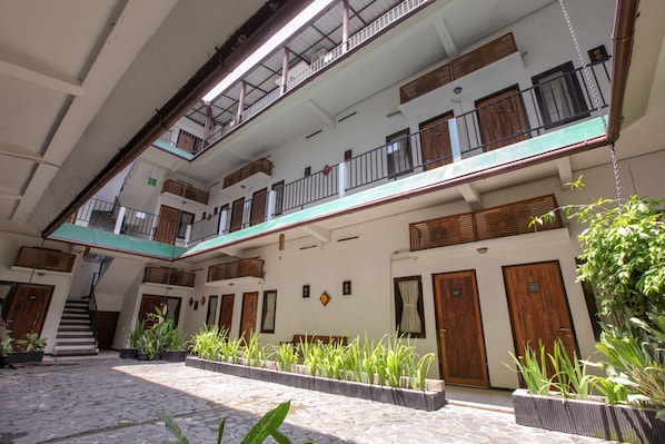 A multi-level courtyard with potted plants, wooden doors, and a staircase. - Mawar Asri Hotel (Yogyakarta)