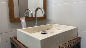 A bathroom sink with a marble basin, a faucet, and a mirror above it. - Mawar Asri Hotel (Yogyakarta)