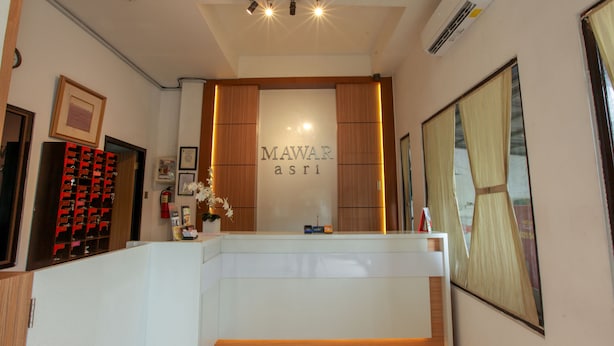 Un comptoir d’accueil avec une pancarte indiquant « MAWAR asri » dans le hall d’un hôtel.