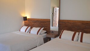 Une chambre d’hôtel avec deux lits, une tête de lit en bois, une table de chevet, un miroir et une lampe fixée au mur.