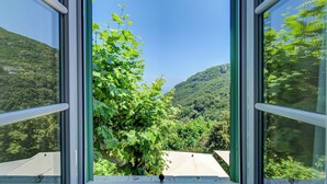 A view through a window with a clear sky and a lush green landscape. - Hotel Restaurant La Corniche (San-Martino-di-Lota)