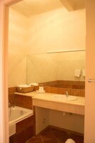 Un baño con bañera, lavabo y espejo.