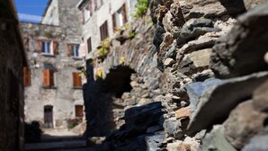 A narrow stone pathway flanked by old stone buildings with arched doorways and wooden shutters. - Hotel Restaurant La Corniche (San-Martino-di-Lota)