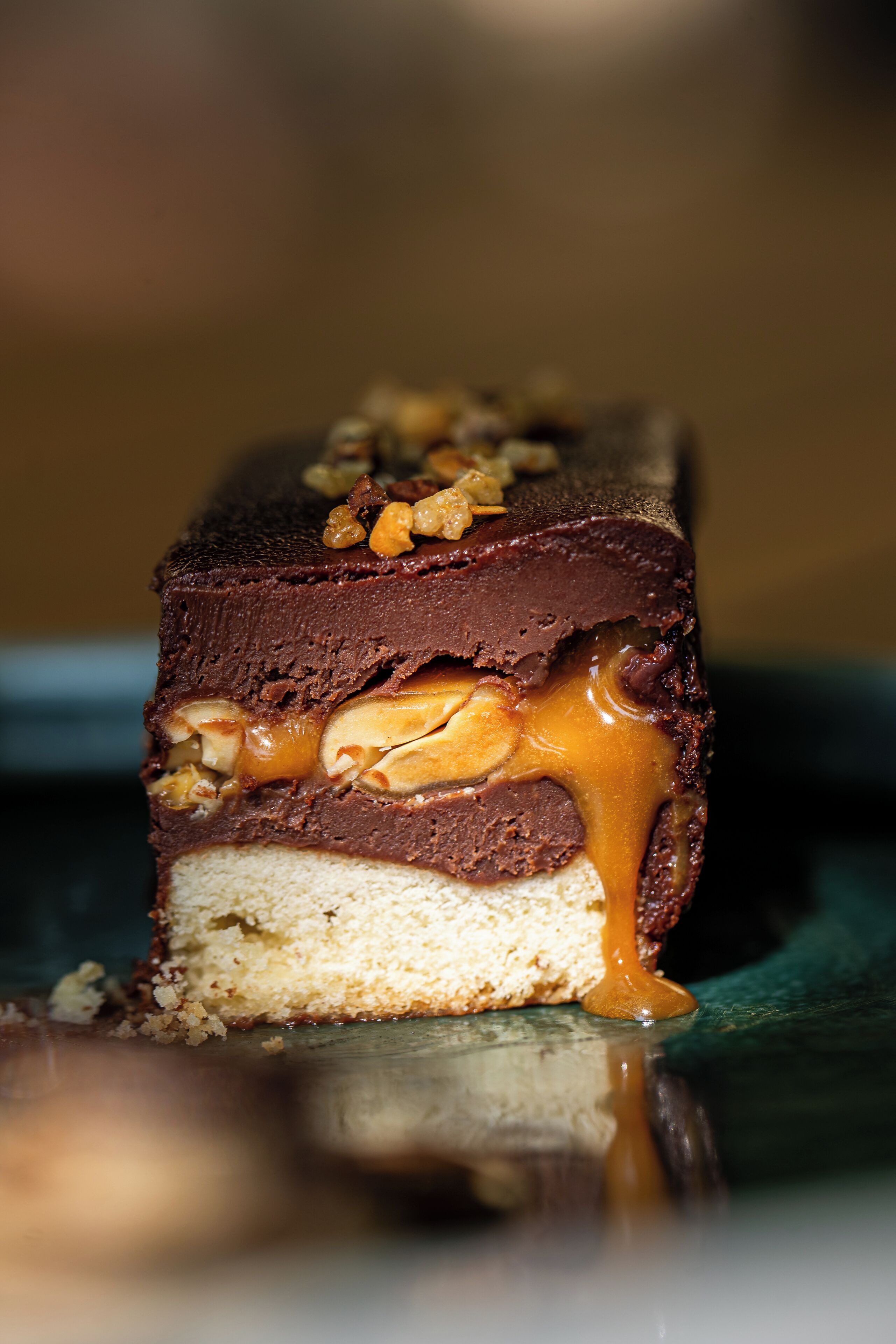 Gros plan d’un dessert à plusieurs couches, avec un cœur au caramel et des noix sur le dessus.