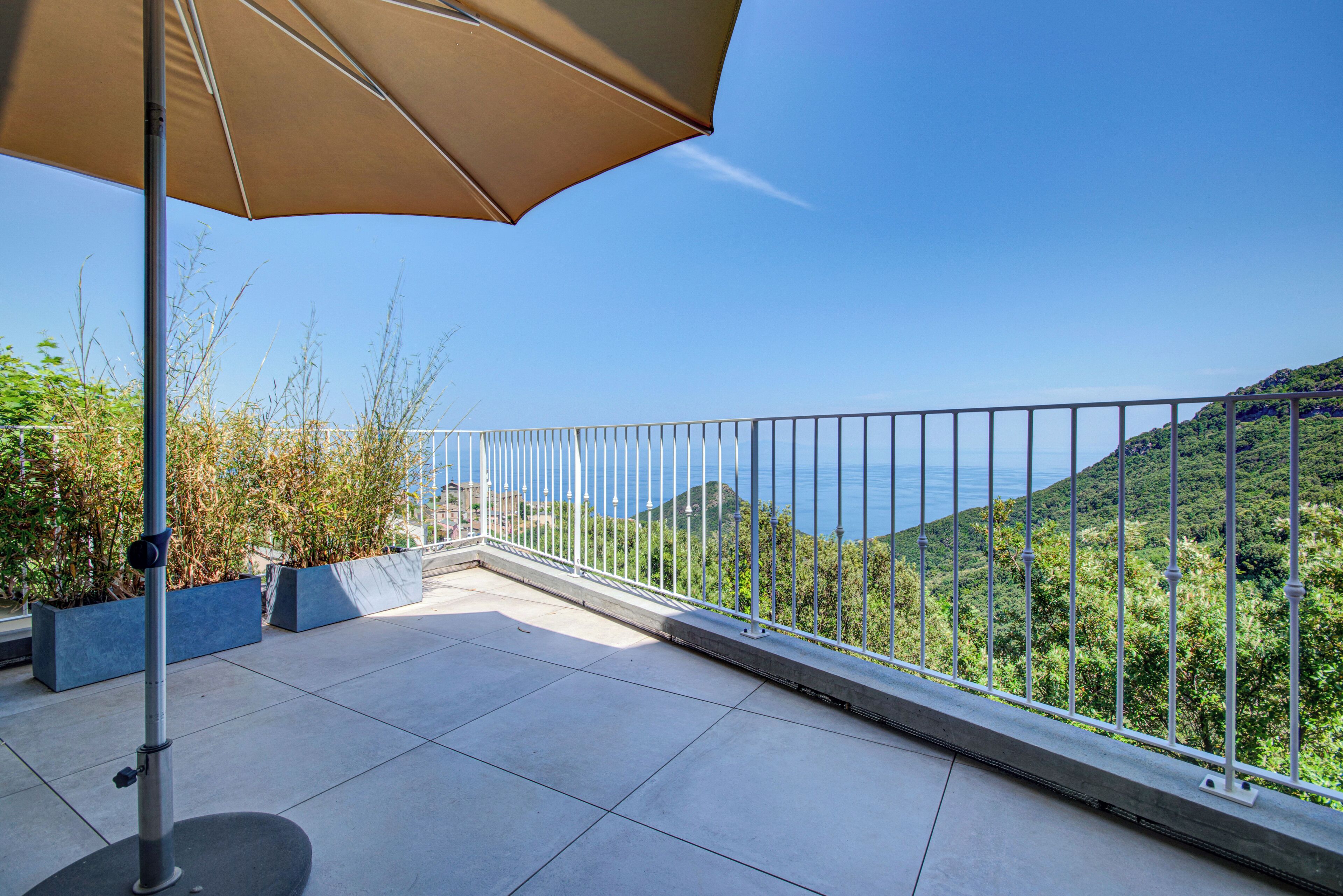 Ein Balkon mit Blick auf das Meer und viel Grün.