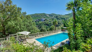 A swimming pool with a view of a mountainous landscape and a building in the background. - Hotel Restaurant La Corniche (San-Martino-di-Lota)