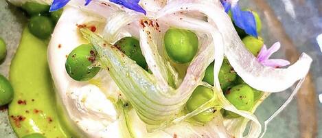A dish with green olives, white creamy sauce, and purple flowers.