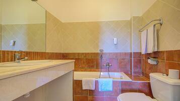 A bathroom with a sink, bathtub, toilet, and a mirror.