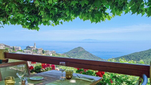 A table set for dining with a view of the sea and a distant mountain. - Hotel Restaurant La Corniche (San-Martino-di-Lota)