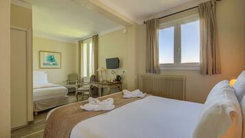 A hotel room with two beds, a desk, a chair, a television, and a window with curtains.