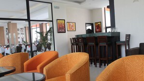 Un hall de hotel con sillones tapizados en color naranja, un mostrador de recepción y obras de arte enmarcadas en las paredes.