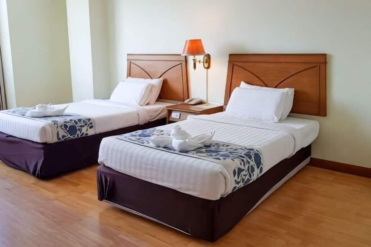 Two single beds with wooden headboards, bedside tables, and lamps.