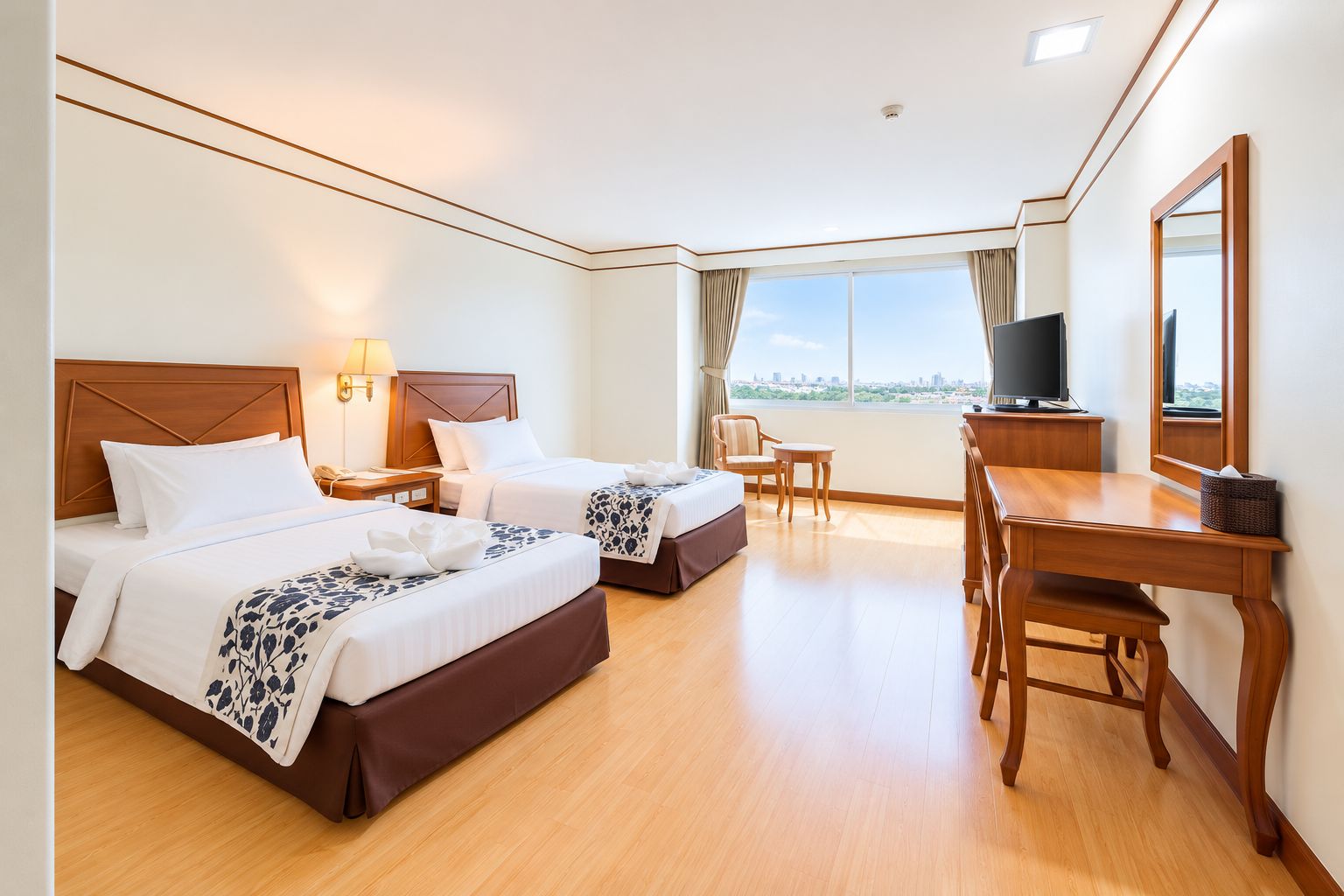 Habitación de hotel con dos camas, un escritorio, una silla, un televisor y un ventanal grande.