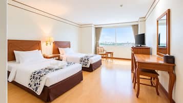 Habitación de hotel con dos camas, un escritorio, una silla, un televisor y un ventanal grande.