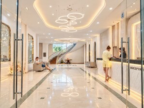 Un moderno vestíbulo de hotel con mostrador de recepción, zona de estar y una escalera.
