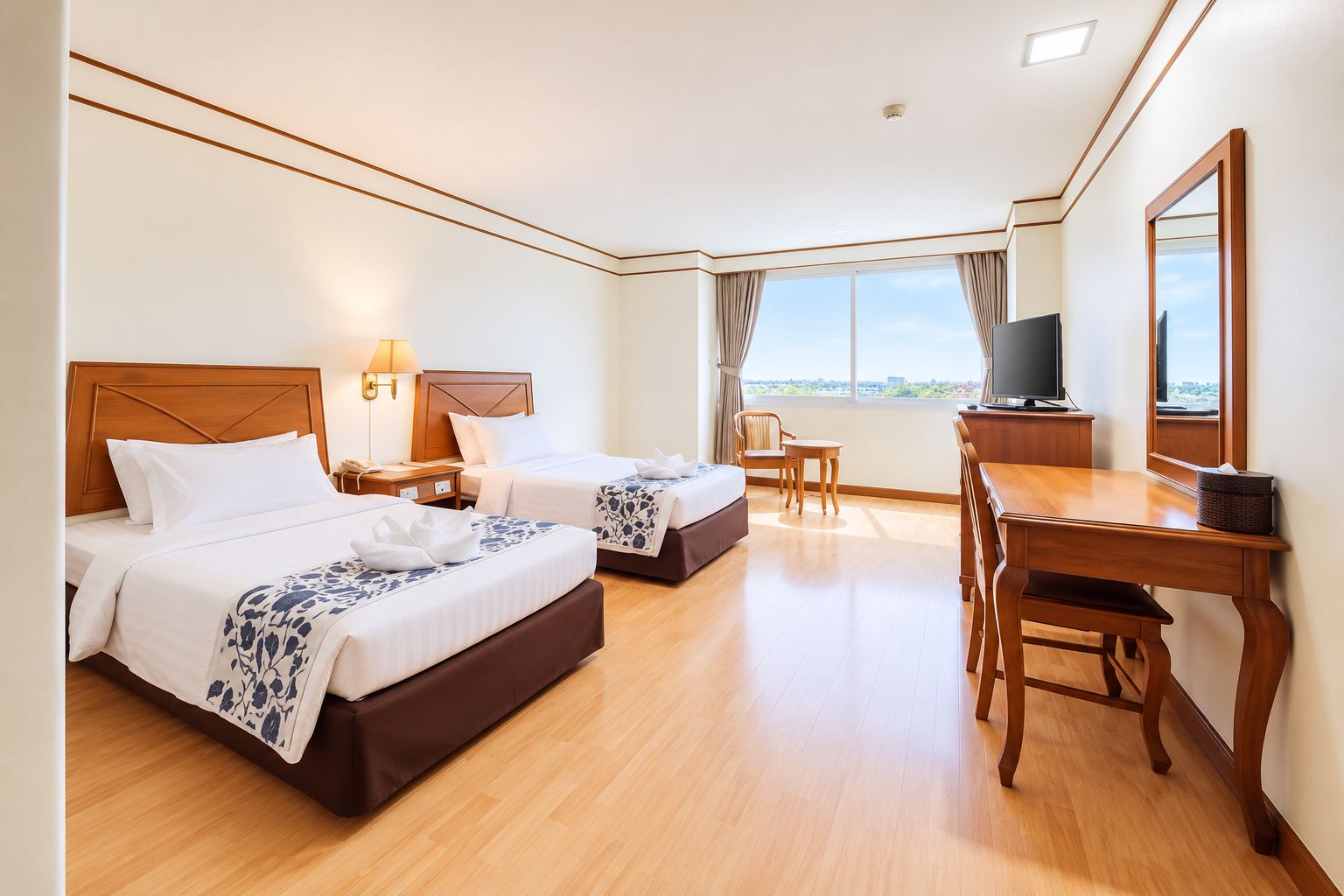 Habitación de hotel con dos camas, un escritorio, una silla, un televisor y un ventanal con cortinas.