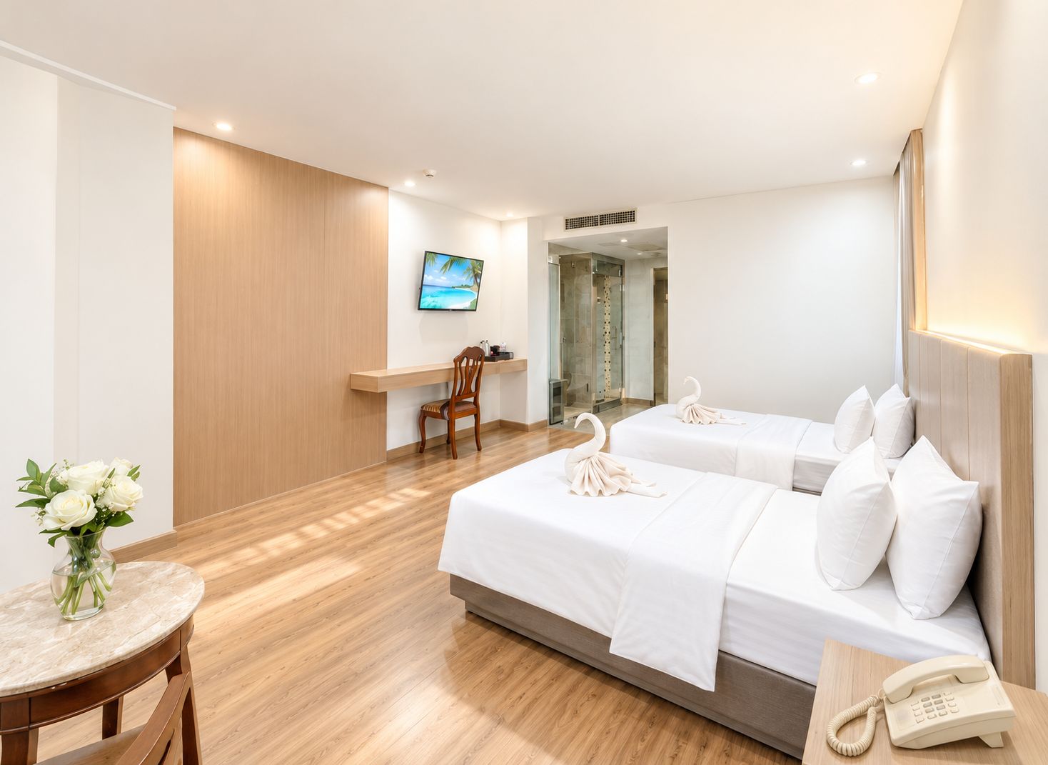A hotel room with two beds, a wooden floor, a TV, a shower, and a telephone.