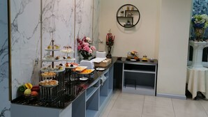 Une cuisine moderne avec des murs en marbre, un îlot central où sont disposés des aliments et des boissons, un éclairage suspendu et une petite étagère ronde agrémentée d’objets décoratifs.