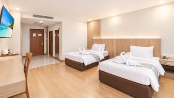 A hotel room with two beds, a desk, and a television.