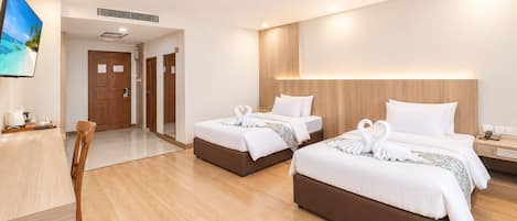 Habitación de hotel con dos camas, un escritorio y un televisor.