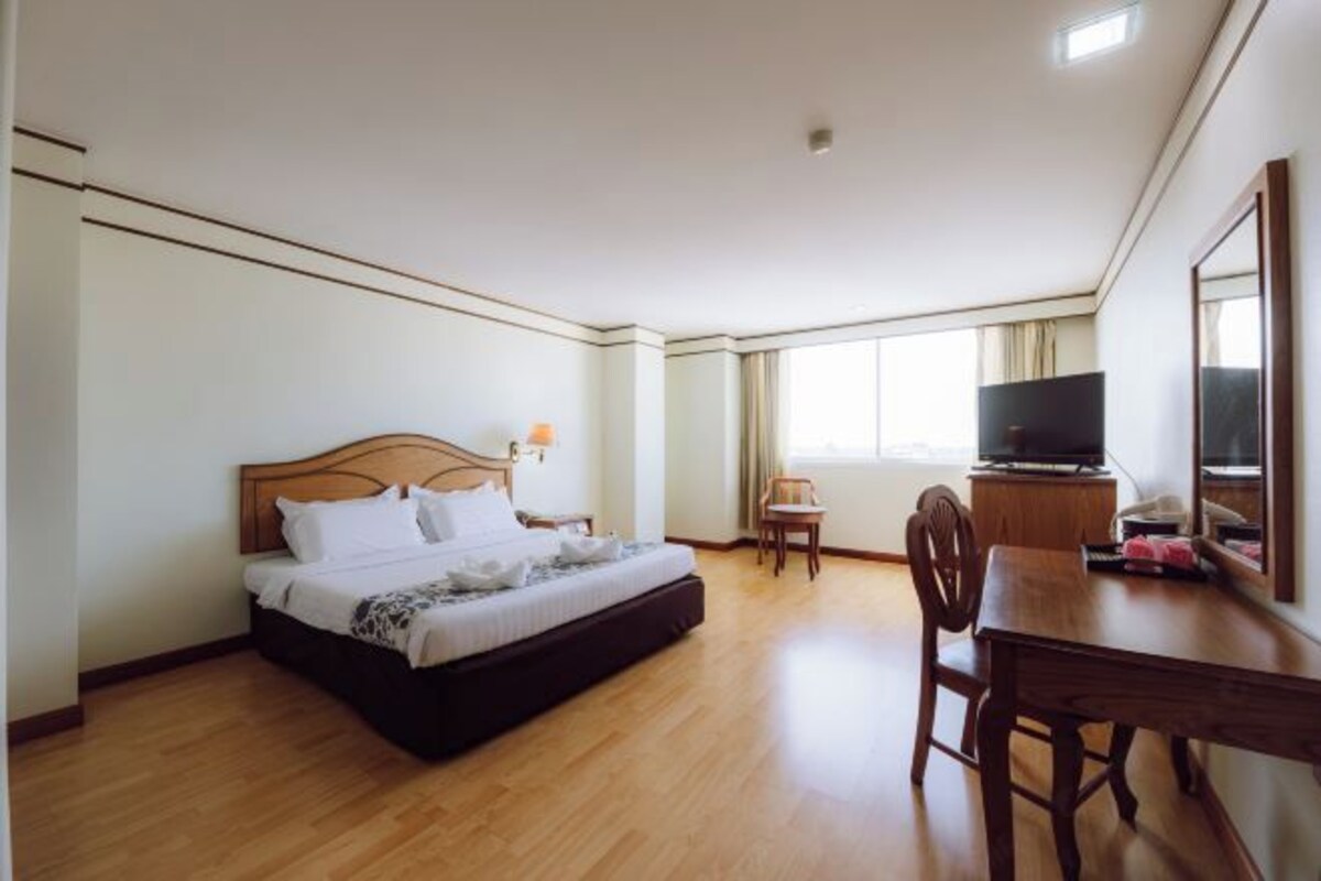 A hotel room with a bed, a TV, a dining table, and a chair.
