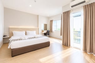 Una habitación de hotel moderna con una cama grande, un escritorio y un balcón con cortinas.