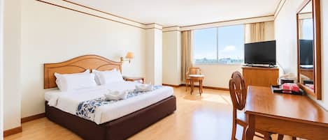 A hotel room with a bed, a desk, a chair, a TV, and a large window.
