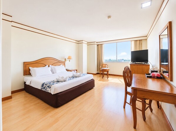 Une chambre d’hôtel avec un lit, un bureau, une chaise, une télévision et une grande fenêtre.